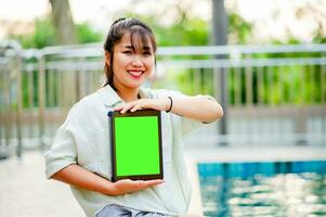 work online communicate online Young woman with ipad working with ipad by swimming pool at home photo