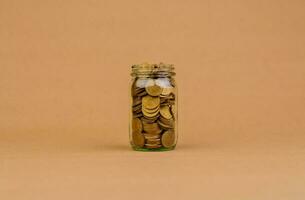 Saving coins in a glass jar Saving money for the future, investment savings, salary, income, expenditure, financial loan, home loan, loan, savings and financial growth concept. photo