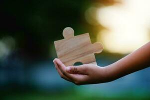 Jigsaw in hand, a puzzle piece that is critical to success. Creativity, ideas, initiative, unity, teamwork photo