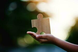 Jigsaw in hand, a puzzle piece that is critical to success. Creativity, ideas, initiative, unity, teamwork photo