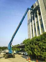 Manlift crane with platform lifting to the roof top of a building photo