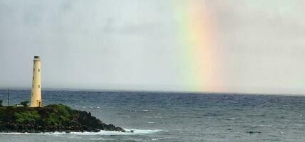 Light house on the pacific ocean with a rainbow in the background photo