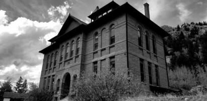 un negro y blanco foto de un antiguo edificio en un pequeño ciudad.