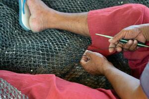 Close up View of Fisherman Fixing Fishng Net photo