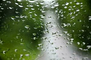 borroso imagen de gotas de lluvia en el posterior ver espejo de auto, suave atención foto