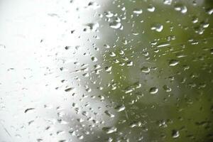 borroso imagen de gotas de lluvia en el posterior ver espejo de auto, suave atención foto