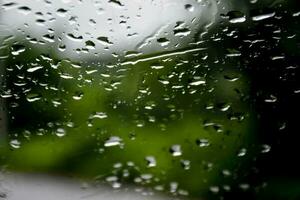 borroso imagen de gotas de lluvia en el posterior ver espejo de auto, suave atención foto