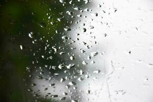 borroso imagen de gotas de lluvia en el posterior ver espejo de auto, suave atención foto