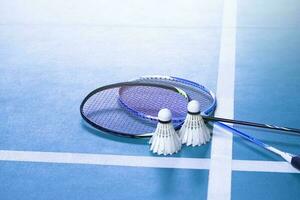 Cream white badminton shuttlecock and racket on floor in indoor badminton court, copy space, soft and selective focus on shuttlecocks. photo