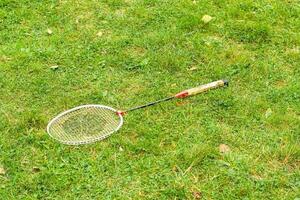 The badminton racket lying on the green grass. photo