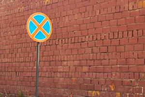 red brick wall and road round crossed out sign. photo