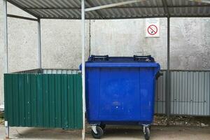 blue plastic trash container and no smoking sign. photo