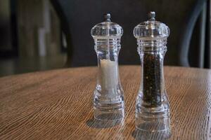 salt pepper in glass flasks on wooden table. photo