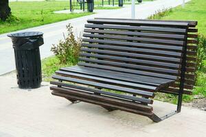 wooden bench and trash can in city park. photo