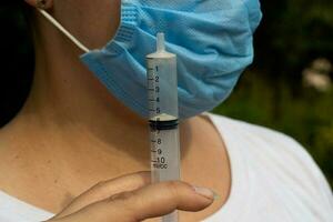 Female face medical blue mask and empty syringe photo