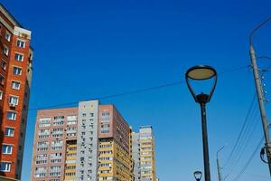poste de luz Encendiendo y de muchos pisos residencial edificios soleado día. azul cielo. foto