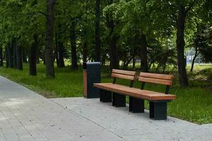 wooden bench with wastebasket on alley in pack. photo