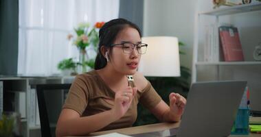 metraggio di contento giovane asiatico donna indossare bicchieri utilizzando un' il computer portatile su un' scrivania nel il vivente camera a casa. stile di vita, attività e persone concetti. video