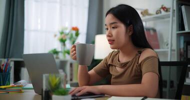 métrage de content Jeune asiatique femme travail avec portable sur une bureau dans le vivant pièce à maison. mode de vie, activité et gens concepts. video