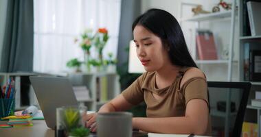 beeldmateriaal van gelukkig jong Aziatisch vrouw werken met laptop Aan een bureau in de leven kamer Bij huis. levensstijl, werkzaamheid en mensen concepten. video