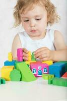 Girl builds up something from colourful geometrical figures and shapes. Closeup photo