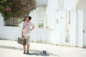 antiguo caucásico mujer es quedarse en el calle con maleta. foto