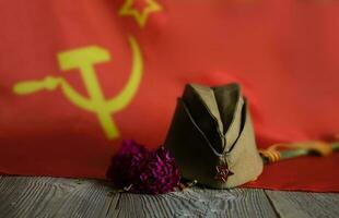 Military cap, carnations, Saint George ribbon on a wooden surface. photo