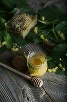 Linden blossoms honey in a glass bottle on a wooden surface. photo