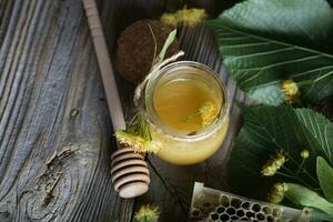 Linden blossoms honey in a glass bottle on a wooden surface. photo