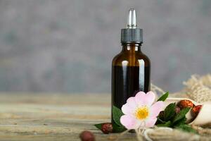 Rose hip syrup in a dark glass dropper bottle on a wooden surface. photo