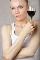 Young lady keeps a glass of red wine in her hand photo