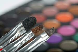 Brushes kit. Makeup palette of eye shadows in the background photo