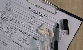 Pen and pill on a mental health intake form. Closeup photo