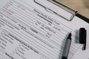 Mental health intake form of a imagine person and a pen on a table. photo