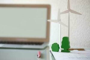 Paper model of wind turbine and model of trees on the table. photo