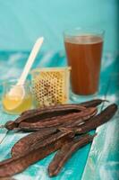 Carob pods and powder on a wooden surface. photo