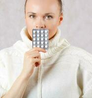 Young caucasian lady  dressed in a knitted sweater with medication. Closeup photo