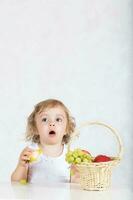 pequeño niña es comiendo Fresco frutas desde un mesa. de cerca foto