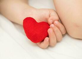 Toddler keeps red plush heart photo