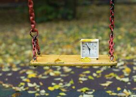 Old square alarm clock on a swing. photo
