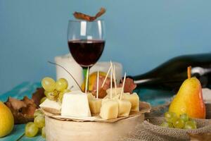 Cheese slices, pear, and grapes on a wooden stand. photo