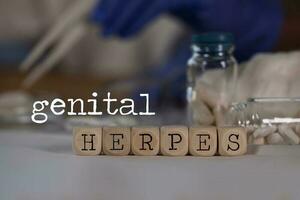 Words GENITAL HERPES composed of wooden dices. Pills, documents and a pen in the background. photo