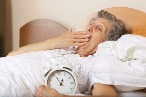 Old woman with vintage alarm clock photo