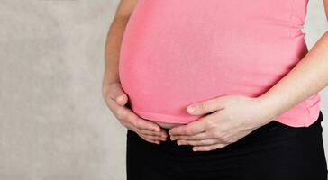 Young pregnan woman keeps her hands at the belly. photo