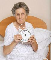 Old woman with vintage alarm clock photo