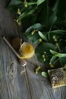 Linden blossoms honey in a glass bottle on a wooden surface. photo