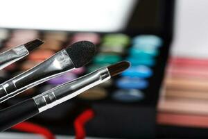 Brushes kit. Makeup palette of eye shadows in the background photo