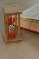 Sand watch on a table. Dictionary in the background. photo
