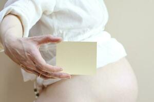 un tarjeta con un brecha en el mano de embarazada foto