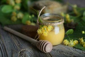 Linden blossoms honey in a glass bottle on a wooden surface. photo